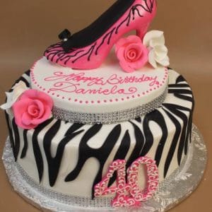 The BD-034 Zebra Shoe is a two-tier zebra-striped cake with pink roses, white flowers, a pink high heel on top, the number 40, and "Happy Birthday Daniela" in pink icing.