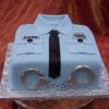GC-053 is a square cake designed as a light blue police uniform shirt with a black tie, silver handcuffs, name badge, and pocket details, set on a silver-patterned cake board.