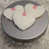 Three CE-003c bridal heart-shaped cookies with white ornate icing and pink flowers are displayed on a silver cake stand with decorative trim, set against a textured white background.
