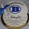 A round white GC-001A Braintree High School cake with a blue B emblem, black "Congratulations Makayla" icing, and a white diploma with blue ribbon on a gold board.