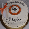 A round white cake with scalloped icing, black dots, a diploma and orange ribbon, reading "Congratulations Makayla" with a Thayer Academy 1877 Braintree, Mass emblem. Product: GC-001L Thayer Academy.
