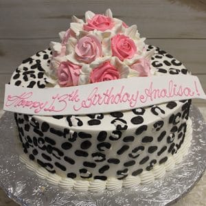 The BD-036E Cheetah Roses cake features round black and white leopard print icing, pink and white frosting roses, and a white "Happy 13th Birthday Analisa!" banner in pink script, presented on a silver tray.