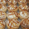 Rows of CO-021 3" Caramel Apple Cheesecakes topped with whipped cream, thin apple slices, and a caramel drizzle.
