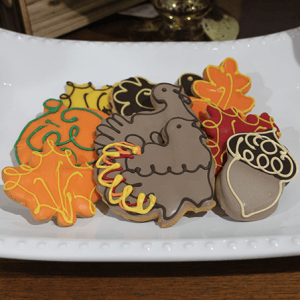 CE-090a Fall Chocolate dipped cookies are decorated in autumn leaf, turkey, and acorn shapes, finished with colorful icing in brown, orange, yellow, and green.