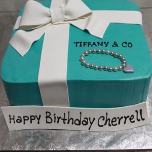 The BD-029 Designer Box Bracelet cake features teal icing, a white fondant bow, a beaded bracelet, and "TIFFANY & CO." text. Cake reads "Happy Birthday Cherrell.