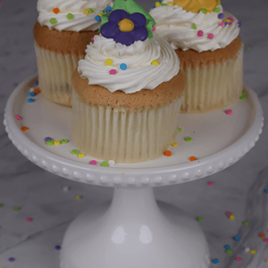 Three gold cupcakes with chocolate filling, displayed on a white cake stand.