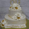 The TC-000L is a two-tier white cake adorned with white and gold roses, gold beads, a large “60” topper, and a “Happy Birthday Myrtho” sign. It is presented on a gold board.