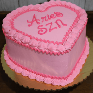 The CB-036A Heart Horoscope cake features a heart shape with pink frosting, piped borders, and "Aries SZN" written in pink icing on top, all presented on a gold cake board.