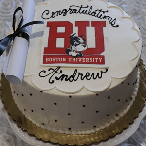 Celebrate with the GC-000C Boston University graduation cake—a round cake with "Congratulations Andrew," featuring the BU logo, mascot, diploma tied in black ribbon, and a quilted pattern with black dots.