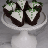 DB-000G Groom Strawberries: Five strawberries dressed in dark and white chocolate tuxedos with green icing details, presented on a white cake stand against a marble background.
