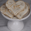 DB-000J Love Cookie: Heart-shaped cookies with white icing, gold accents, and “Love” written on top, displayed on a white pedestal plate against a marble background.