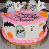 The HW-000C is a Halloween-themed birthday cake with pink frosting, decorated with ghosts, bats, pumpkins, tombstones, and a skull, featuring "Happy Birthday Grace" on top.