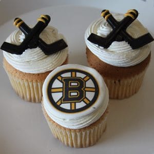Three CC-117B Gold cupcakes with chocolate filling; two have crossed black hockey stick toppers, and the center features the Boston Bruins logo.
