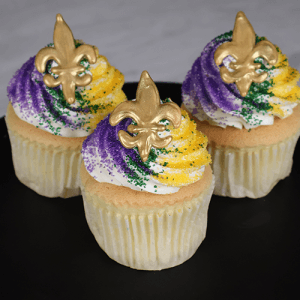 A CC-141 Gold cupcake with chocolate filling and gold fleur-de-lis decoration sits on a black plate.