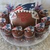 ST-002B Chocolate cupcakes and a football-shaped cake with New England Patriots logos, red, white, and blue star sprinkles, sparkling toppers, and “Happy Birthday Kairo” in red icing.