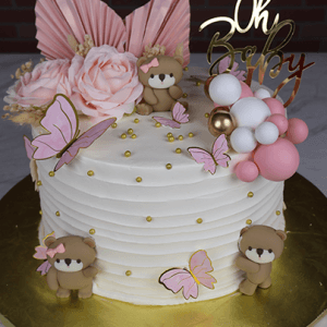 The BB-000F is a round white cake adorned with pink and gold butterflies, teddy bear toppers, faux flowers, balloons, and an “Oh Baby” topper—ideal for a baby shower.