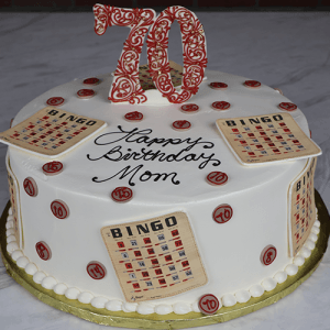The BD-051 is a round white cake featuring bingo cards, red bingo numbers, a large red "70" topper, and “Happy Birthday Mom” written in black icing on top.
