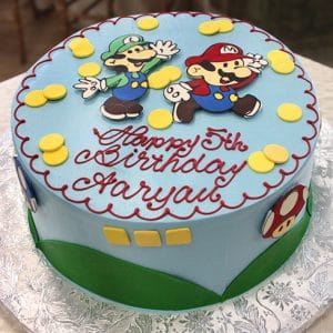 The CB-011T is a round blue birthday cake featuring Mario and Luigi, yellow coins, red "Happy 5th Birthday Aaryan" lettering, and Mario-themed designs on the sides.