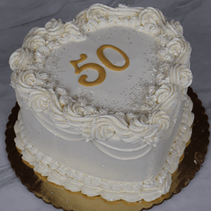 The CB-036C is a round white frosted cake with piped rosettes and a gold "50" topper, displayed on a gold cake board against a marble background.