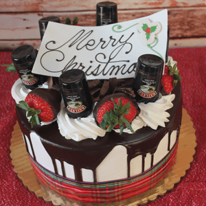 The CH-010 Display Baileys with Christmas Decor features a festive cake topped with chocolate drizzle, whipped cream, strawberries, Baileys mini bottles, and a “Merry Christmas” sign on a gold board against a red textured background.