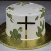 The RC-001F is a white frosted cake with green and gold leaf decorations, gold sugar pearls, and a shiny gold cross on the side, presented on a gold cake board.