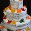 WD-023 is a three-tiered cake styled as birch bark with colorful autumn leaves, a heart with S + B carved on the middle tier, and is presented on a silver foil-covered base.