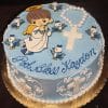 Round blue cake (RC-081) featuring an angel, small blue birds, white rosary and cross, with "God Bless Kayden" in blue icing. White crosses and floral designs decorate the sides.