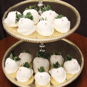 The ST-007-Bride Strawberries are white chocolate-dipped treats shaped like bunnies, featuring pink candy noses, dot eyes, and green leafy tops, beautifully arranged on a two-tiered gold serving tray.