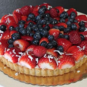 The GD-022 Mixed Berry Fruit Tart features fresh strawberries, blueberries, raspberries, and shredded coconut on top, presented on a gold board against a neutral background.