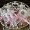 RC-116 features white cross-shaped lollipops wrapped in plastic and tied with pink ribbons, beautifully arranged on a two-tiered silver tray—perfect for religious celebrations or events.