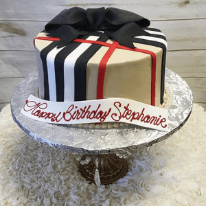 The BD-032 Designer Plaid is a round cake with black, white, and red stripes, topped with a large black bow on a silver stand. A white banner reads "Happy Birthday Stephanie" in red script.