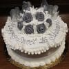 The AN-003 is a round cake with white icing, gray and white fondant roses, "Happy Sweet 16 Shivani" written on top, decorative ribbon accents, and presented on a gold tray.