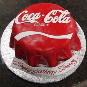 The BD-025 Coca Cola cake is round, designed as a red Coca-Cola Classic can with a white logo and wave. A base banner says "Happy Birthday Timothy" in red script.