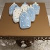 CE-004b baby shower blue and white bottle-shaped cookies with icing are displayed on a gold stand adorned with hanging crystal beads.