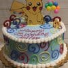 The SC-009 Pokemon cake is round with colorful swirls, candles, a Pikachu cutout topper, balloon decorations, and "Happy Birthday" written in red icing.