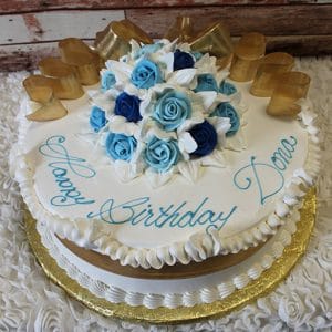 The AN-005 is a round white birthday cake with blue and white icing roses, gold ribbon accents, and "Happy Birthday Dana" in blue script. The cake is presented on a gold board.