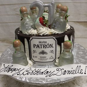 The BD-024V birthday cake features mini Patron tequila bottles, a silver 21 topper, chocolate drips, and strawberries. A white plaque with "Happy Birthday Danielle!" in cursive completes the festive design.