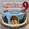 The CB-011A is a blue Roblox-themed birthday cake featuring a "Happy Birthday Trevor" message, cityscape decorations, cartoon character face, a red number 9 candle on top, and a Roblox sign.