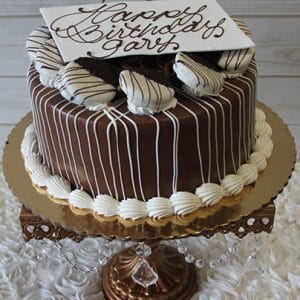 The BD-013A chocolate Oreo cake features white icing drizzles, chocolate-dipped cookies on top, and a white “Happy Birthday Gary” plaque, displayed on a gold stand with crystal accents.