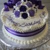 The AN-007 is a round white cake topped with purple and white roses, a purple ribbon, and "Happy Birthday Love" in purple icing. Presented on a silver platter.