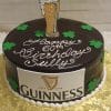 The BD-024G Guinness is a round chocolate cake with green shamrocks, a pint of beer topper, "Happy 60th Birthday Sully," a Guinness logo on the side, and is presented on a gold board.