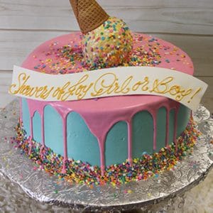 The BB-071 cake features a round design with blue frosting, pink icing drips, colorful sprinkles, and a sprinkle-covered ice cream cone topper with a "Shower of Joy Girl or Boy!" banner on a silver cake stand.