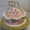 The BD-039 is a pink and white round cake with roses and gold accents, featuring the number 50 on top and sides—perfect for a 50th birthday or anniversary. It sits on a gold board.