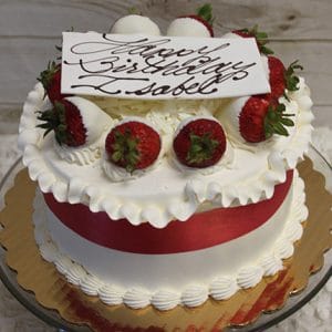 The BD-012 White dipped strawberry decor is a round white frosted birthday cake with a red ribbon, chocolate-dipped strawberries, and a "Happy Birthday, Isabel" white chocolate plaque, displayed on a gold cake board.