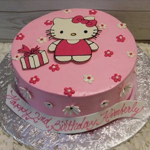 The CB-009W is a pink birthday cake with a Hello Kitty figure, white and pink flowers, a gift box, and “Happy 2nd Birthday Kimberly” written in pink icing on the side.