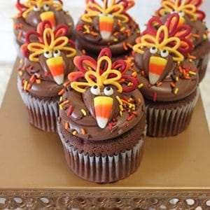 Six CC-070 Turkey cupcake design chocolate cakes with white mousse filling, topped with candy corn and colorful icing for feathers, displayed on a decorative gold stand with crystal accents.