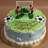 The SC-054 Soccer cake is a round birthday cake topped with a soccer field, two players, a goalie, and a goal. "Happy 6th Birthday Jeffroy" is written on it, with soccer ball designs decorating the sides.