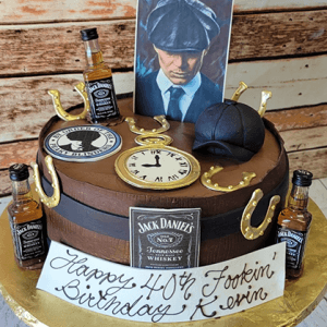 The BD-071B is a round Jack Daniel’s-themed cake featuring mini whisky bottles, gold horseshoes, a clock face, flat cap, man’s portrait, and a plaque that says “Happy 40th Fookin Birthday Kevin.”.