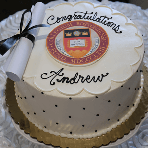 The GC-000A Boston College cake is white with black polka dots, a gold-trimmed base, “Congratulations Andrew” in black icing, topped with the Boston College seal and a white diploma tied with a black ribbon.